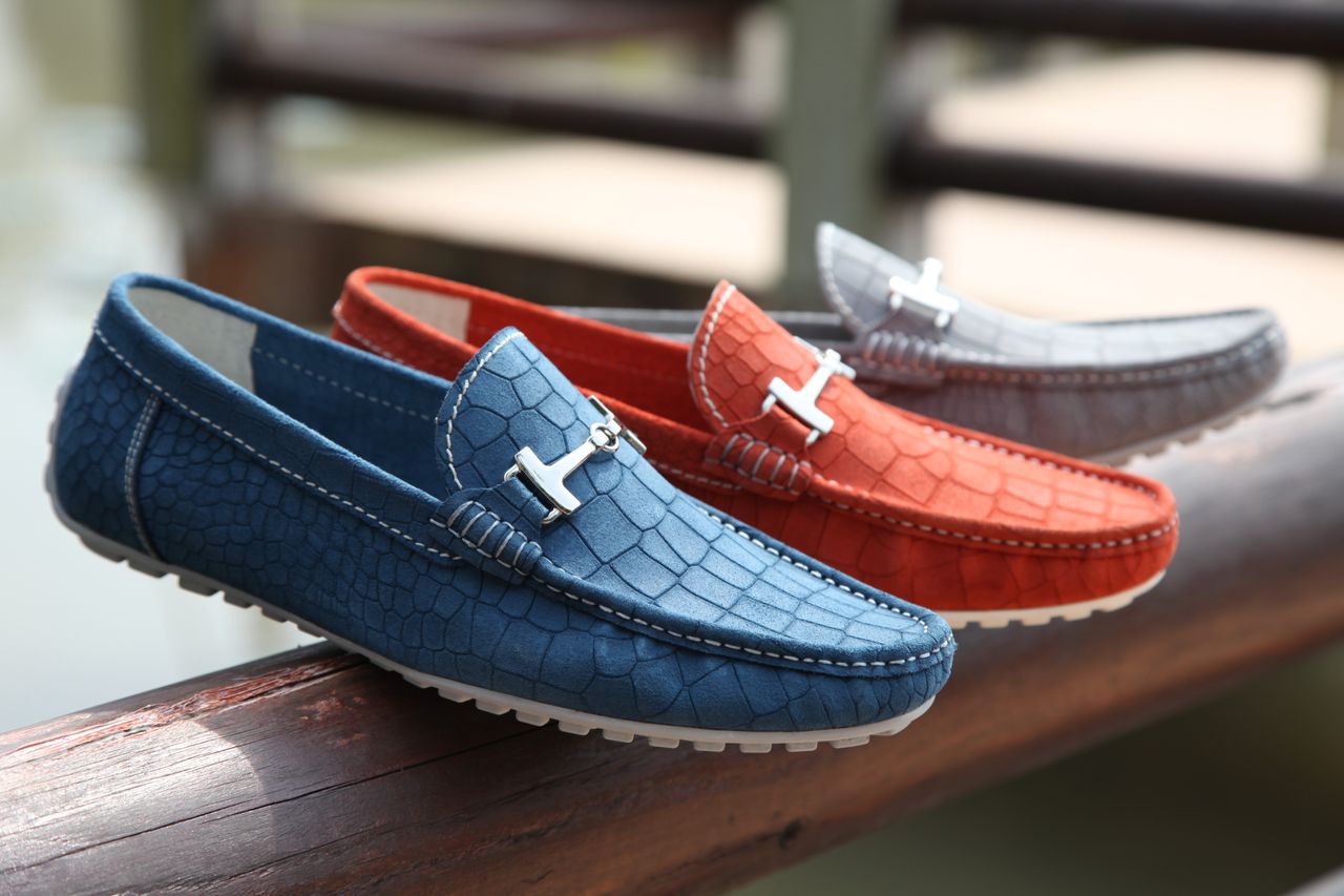 home-hero Fashionable leather loafers in various colors displayed on a wooden railing outdoors.