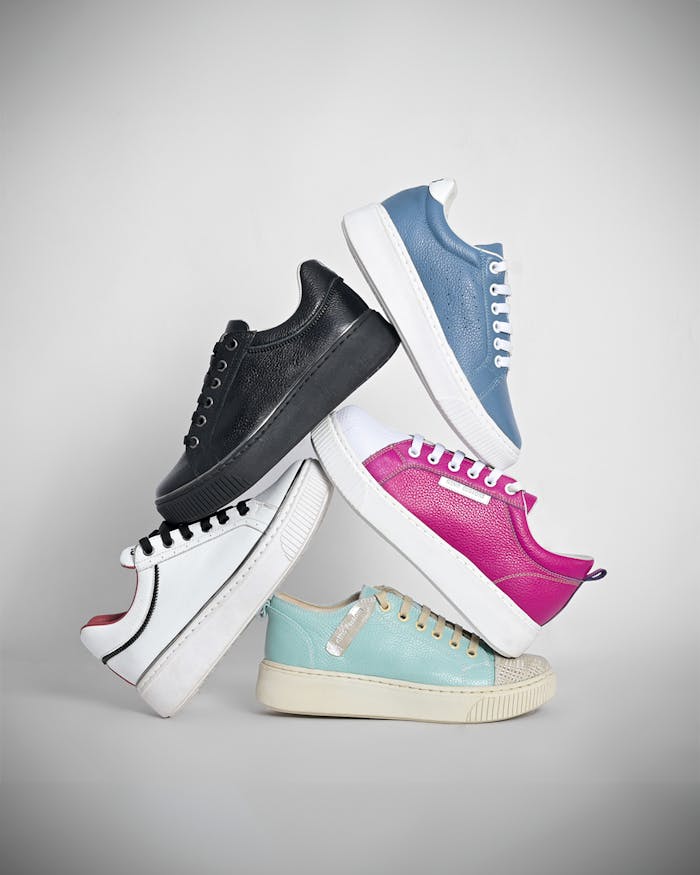 services-05 A creative display of five stacked colorful sneakers on a gray background.