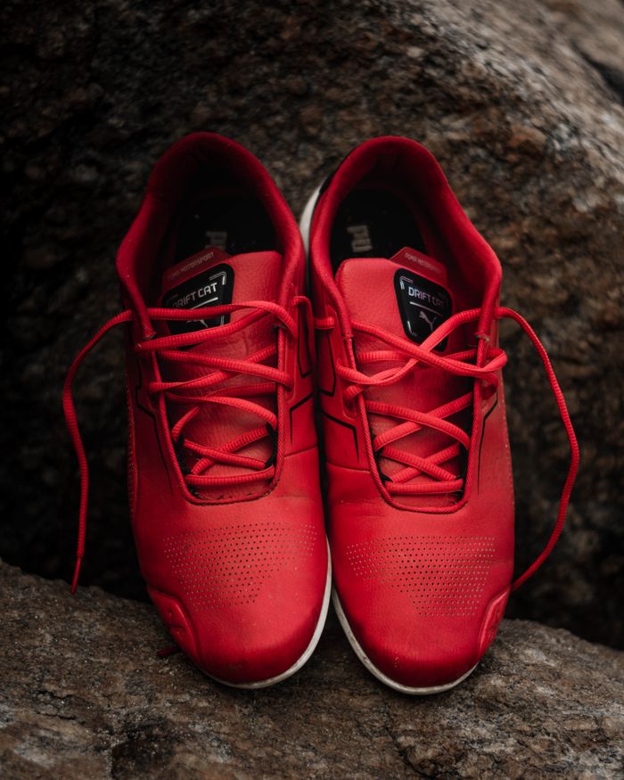 services-06 Red leather sneakers placed on rocks, perfect for fashion and sports themes.